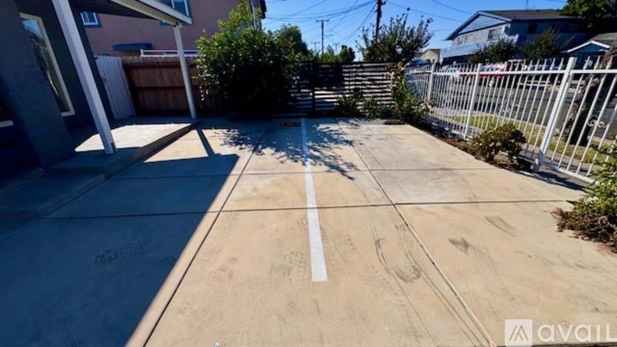 A concrete driveway with a white line down the middle leading to a house.