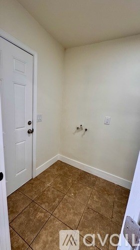 A room with a white door and brown tile flooring.