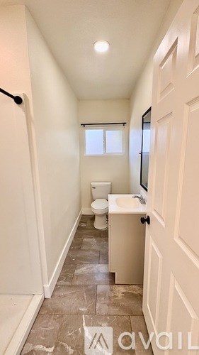 A bathroom with a toilet, sink, and a window.
