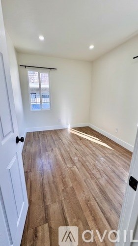 A room with wooden flooring and a window with blinds.
