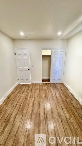 A room with wooden flooring and two doors, one of which is open.