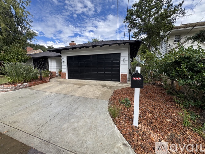 A white house with a black garage door and a white fence.