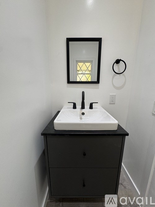 A white sink is on a black cabinet in a bathroom.
