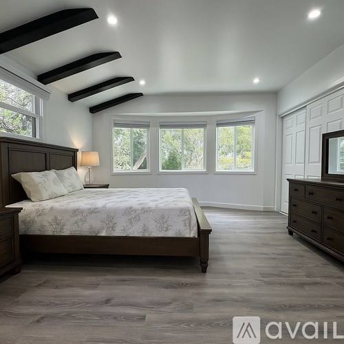 A bedroom with a bed, dresser, and window.