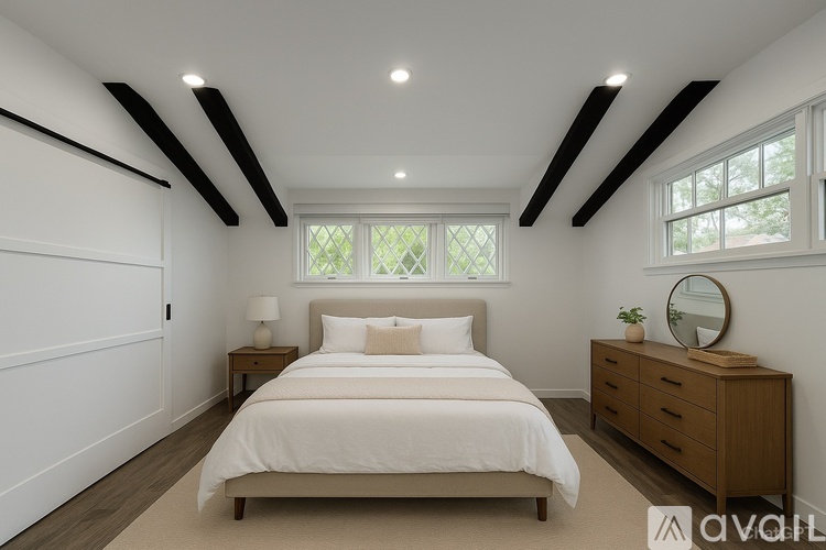 A bedroom with a bed, nightstand, and a window with a view of trees.