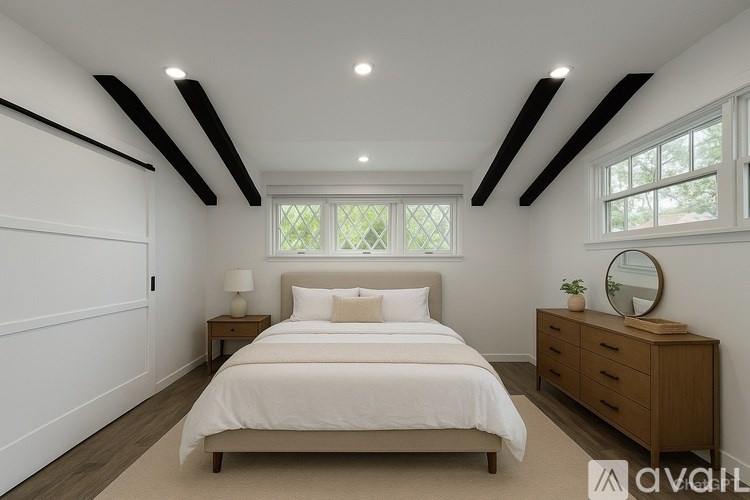A bedroom with a bed, nightstand, and a window with a view of trees.