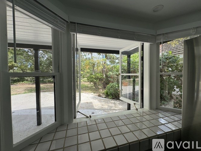 A room with a tiled floor and sliding glass doors leading to a garden.