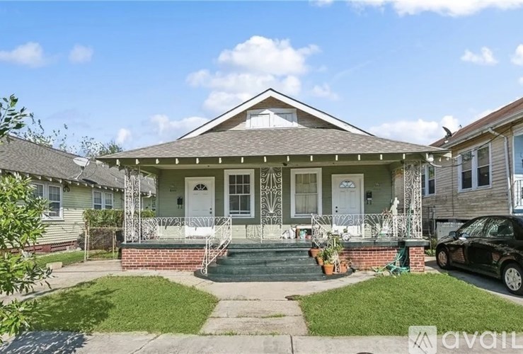 A house with a front porch and a car parked in front.