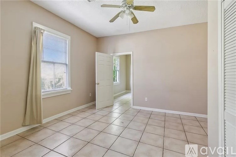 A room with a ceiling fan and a door leading to another room.