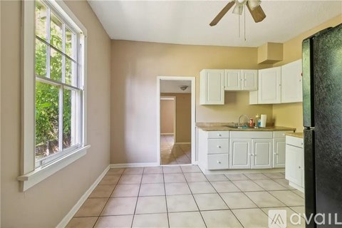 A kitchen with white cabinets and a black refrigerator.