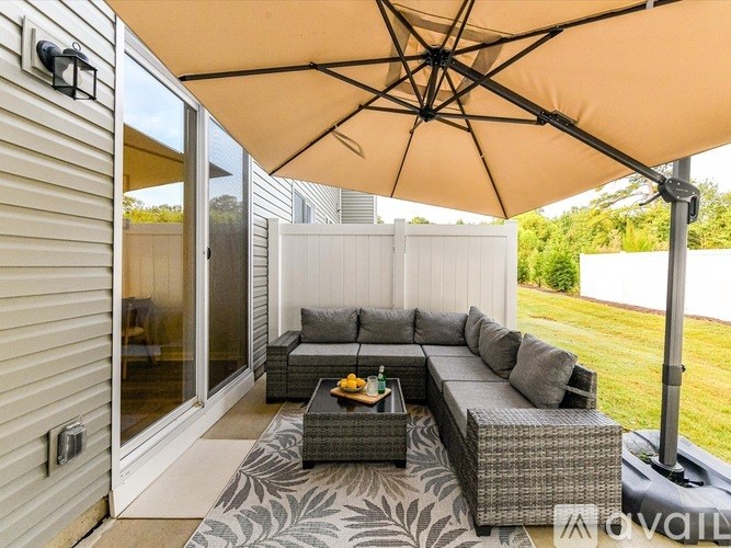 A patio with a grey couch and a beige umbrella.
