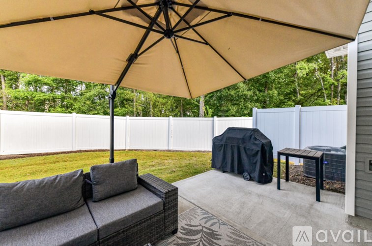 A patio with a grey couch and a large umbrella.