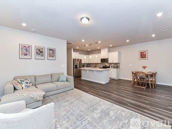 A living room with a grey sofa and a dining table with chairs.