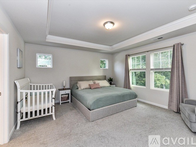 A bedroom with a white crib and a bed with a green bedspread.