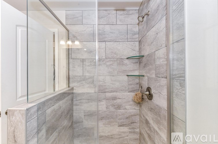 A bathroom with a marble tile wall and a glass shelf.