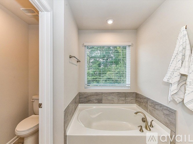 A bathroom with a toilet, sink, and window.