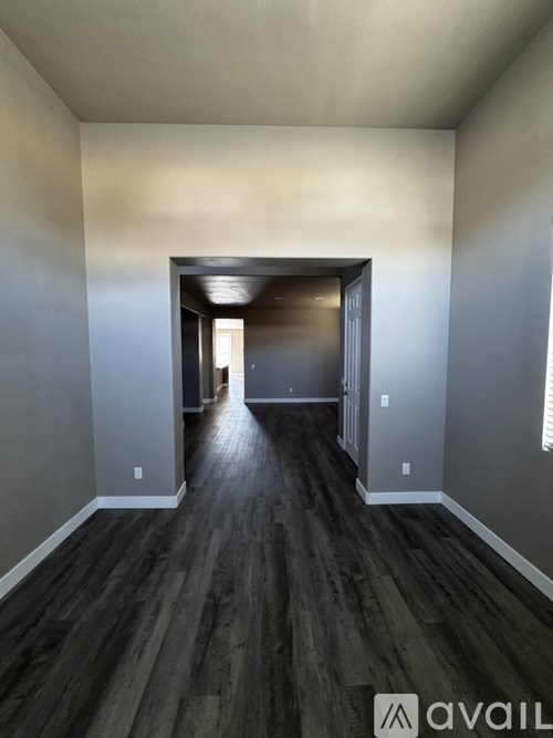 A hallway with dark wood flooring and white walls.