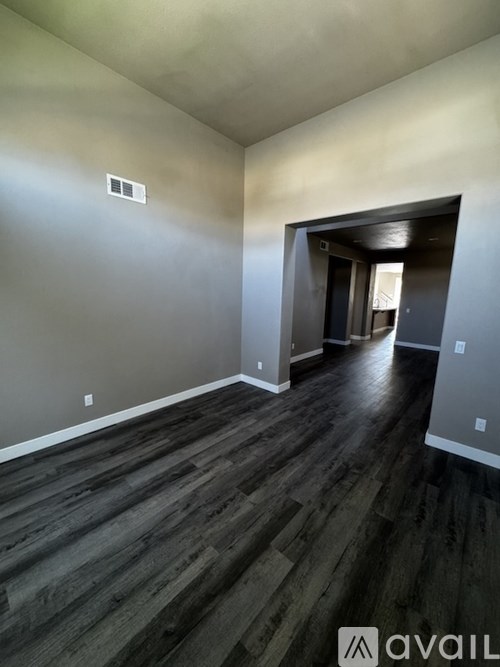 A room with wooden flooring and a doorway leading to another room.