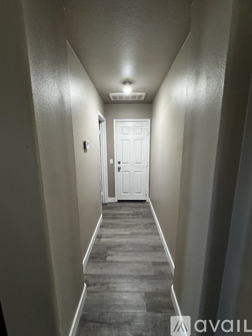 A long hallway with a white door at the end.