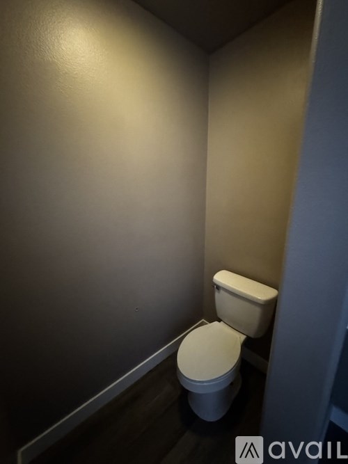 A white toilet in a small room with a dark floor.