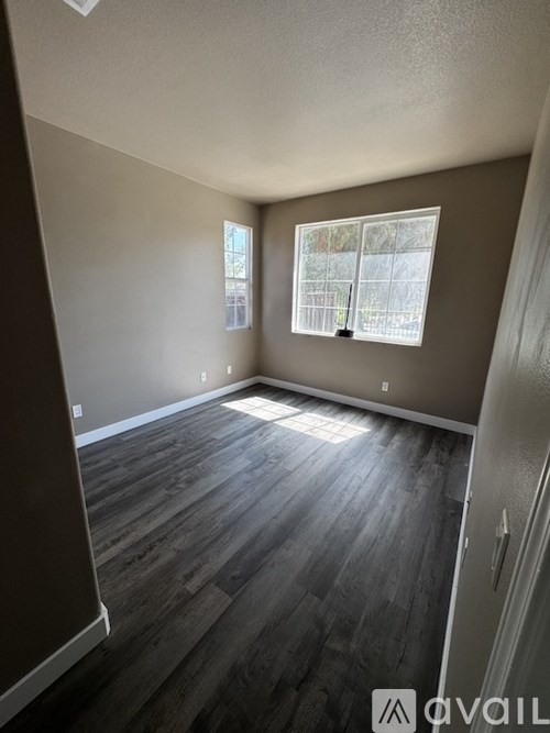A room with wooden flooring and a window with blinds.