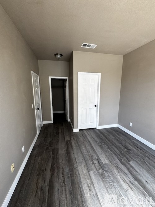 A room with a white door and a grey floor.