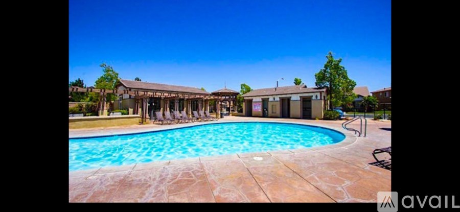 A large swimming pool surrounded by a patio and a covered area.