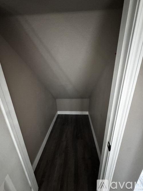 A long, narrow hallway with dark wood flooring and white walls.