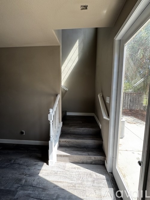 A hallway with a staircase leading to a door.