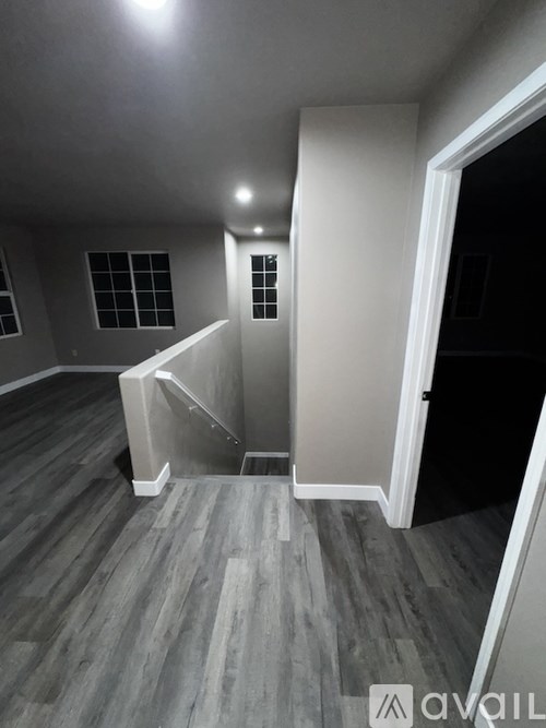 A room with wooden flooring and a staircase leading to another room.