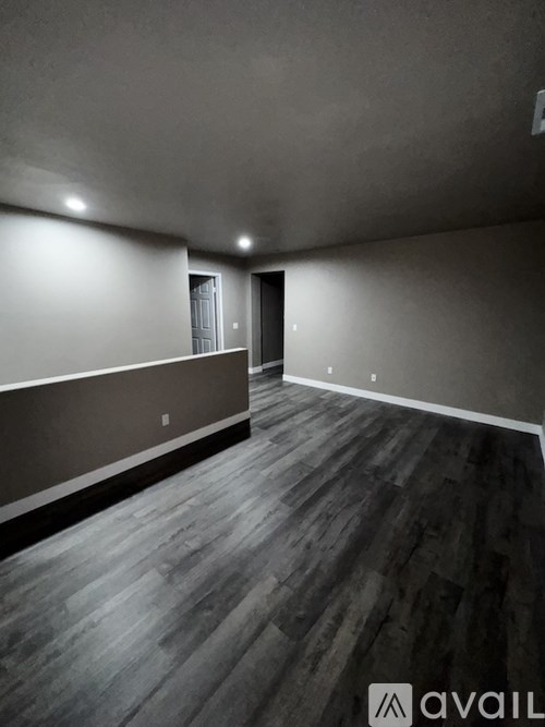 A room with wooden flooring and a door in the background.