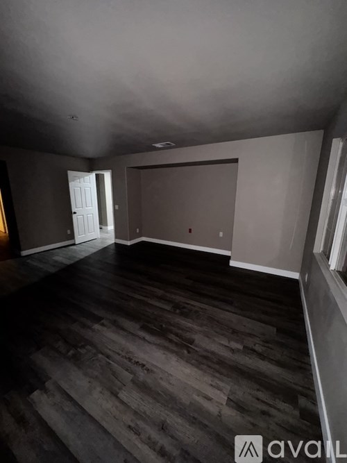 A room with wooden flooring and a large window.