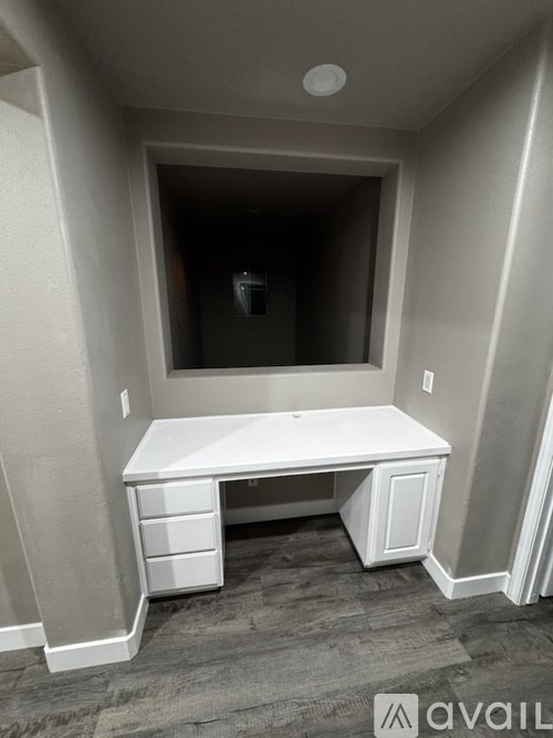 A white desk with drawers is in a room with a carpeted floor.