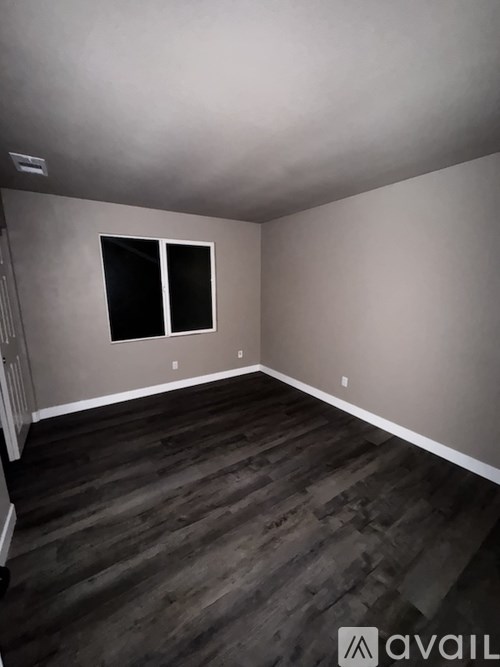 A room with a window and wooden flooring.