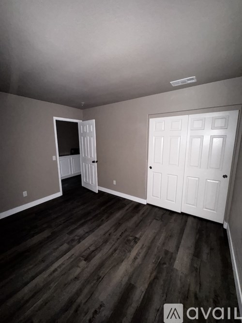 A room with wooden floors and two doors, one of which is open.