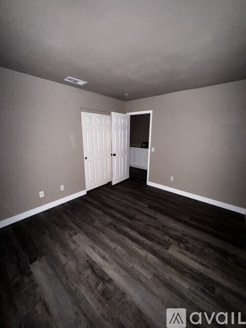 A room with a wooden floor and two white doors.