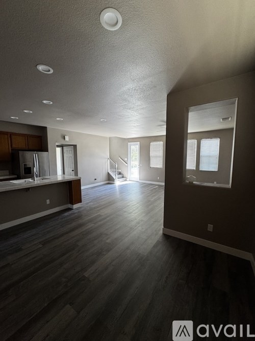 A spacious room with wooden flooring and a large mirror on the wall.
