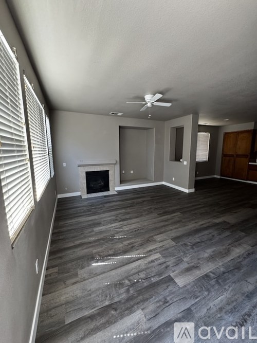 A living room with a fireplace and a ceiling fan.