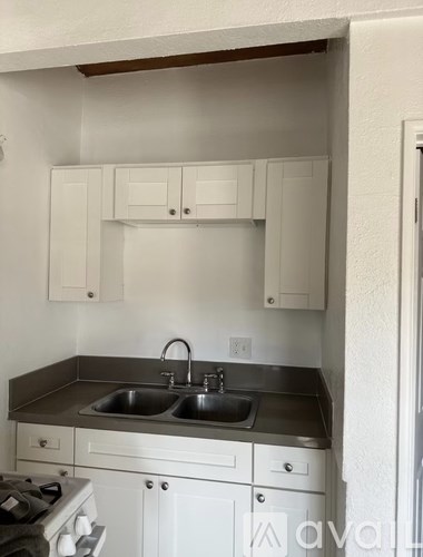 A kitchen with white cabinets and a stove top oven.
