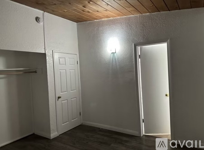 A small room with a white door and a wooden ceiling.