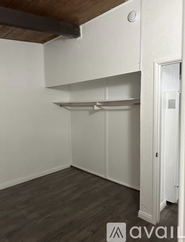 A white kitchen with a wooden ceiling and grey flooring.
