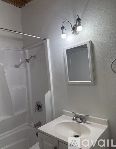 A bathroom with a white sink and a shower.