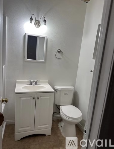 A white bathroom with a toilet, sink, and mirror.