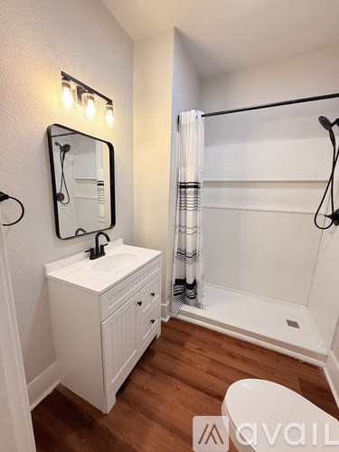 A white bathroom with a wooden floor and a white toilet.