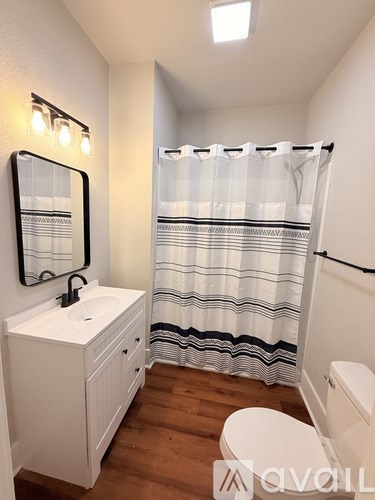 A white bathroom with a wooden floor and a white toilet.