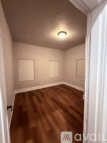 A hallway with wood flooring and two empty picture frames on the wall.