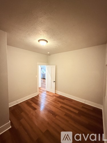 A room with wooden floors and a doorway leading to another room.