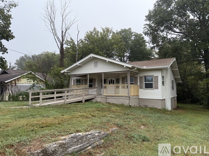 A house with a porch and a fence in front of it.