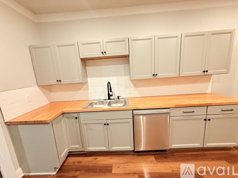 A kitchen with white cabinets and a wooden countertop.