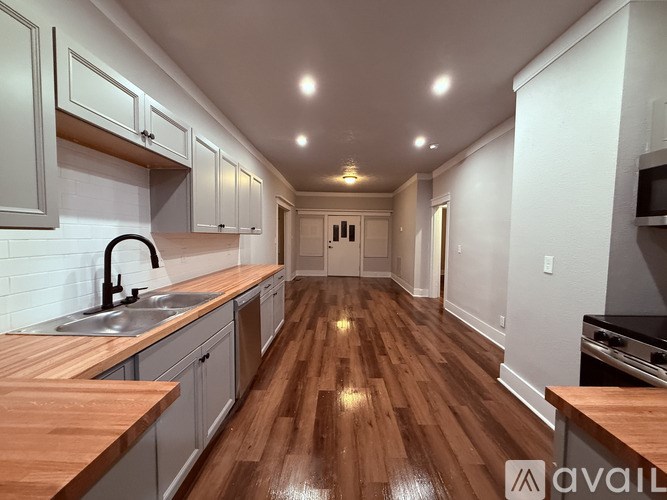 A kitchen with wooden floors and grey cabinets.